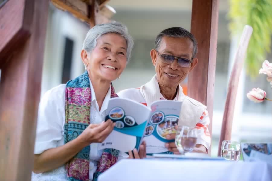 ครอบครัวผู้สูงอายุนั่งอ่านเอกสารแนะนำบริการของศูนย์ด้วยกัน