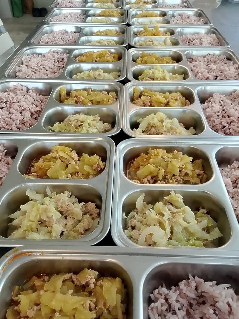 ถาดหลุมสแตนเลสจัดข้าวกล้องไรซ์เบอร์รี แกงฟักเขียวหมูสับ และผัดกะหล่ำปลีหมูสับ เรียงรอเสิร์ฟ